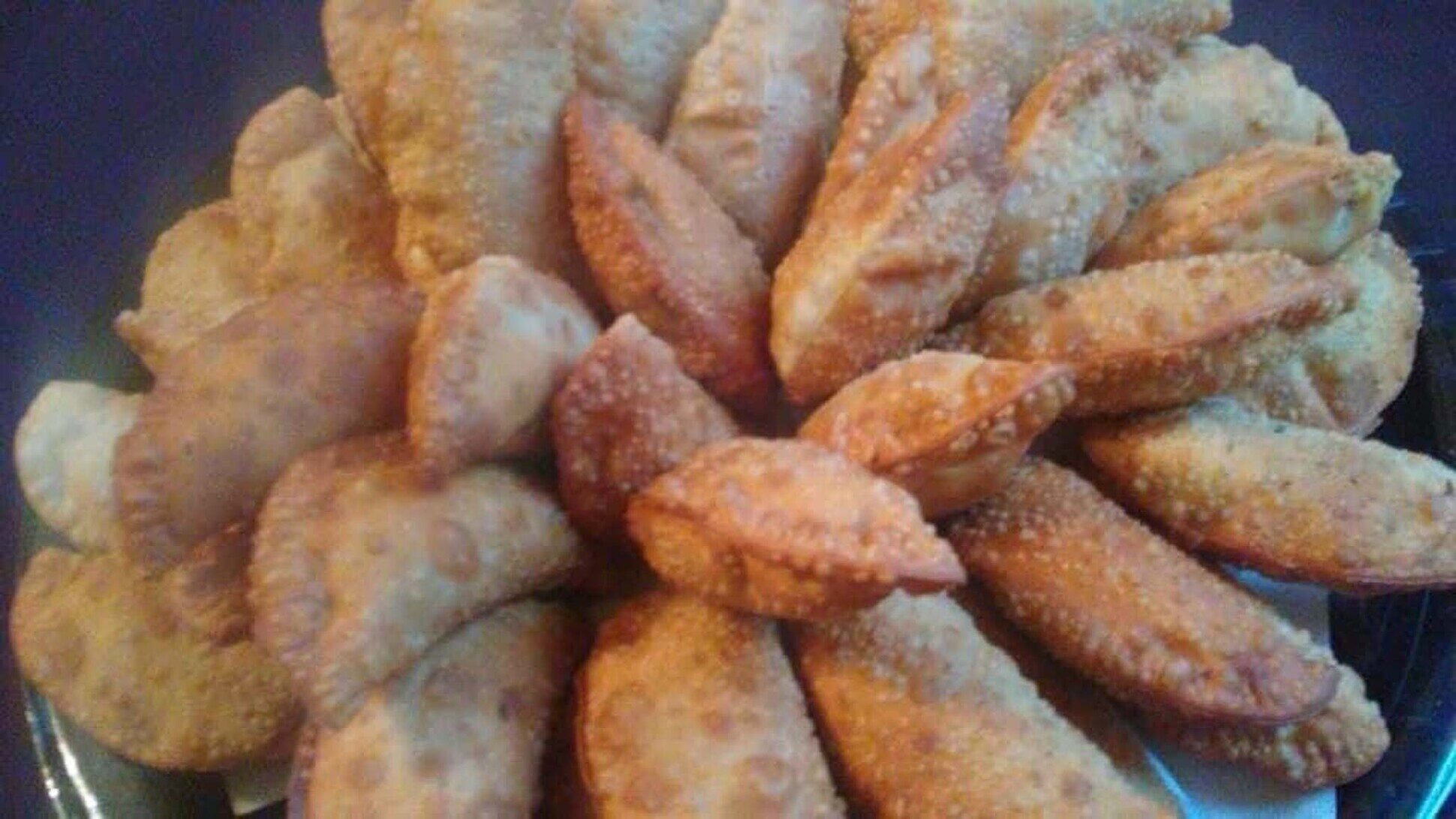 A tray of hand-folded empanadas fresh from the oven, arranged for service