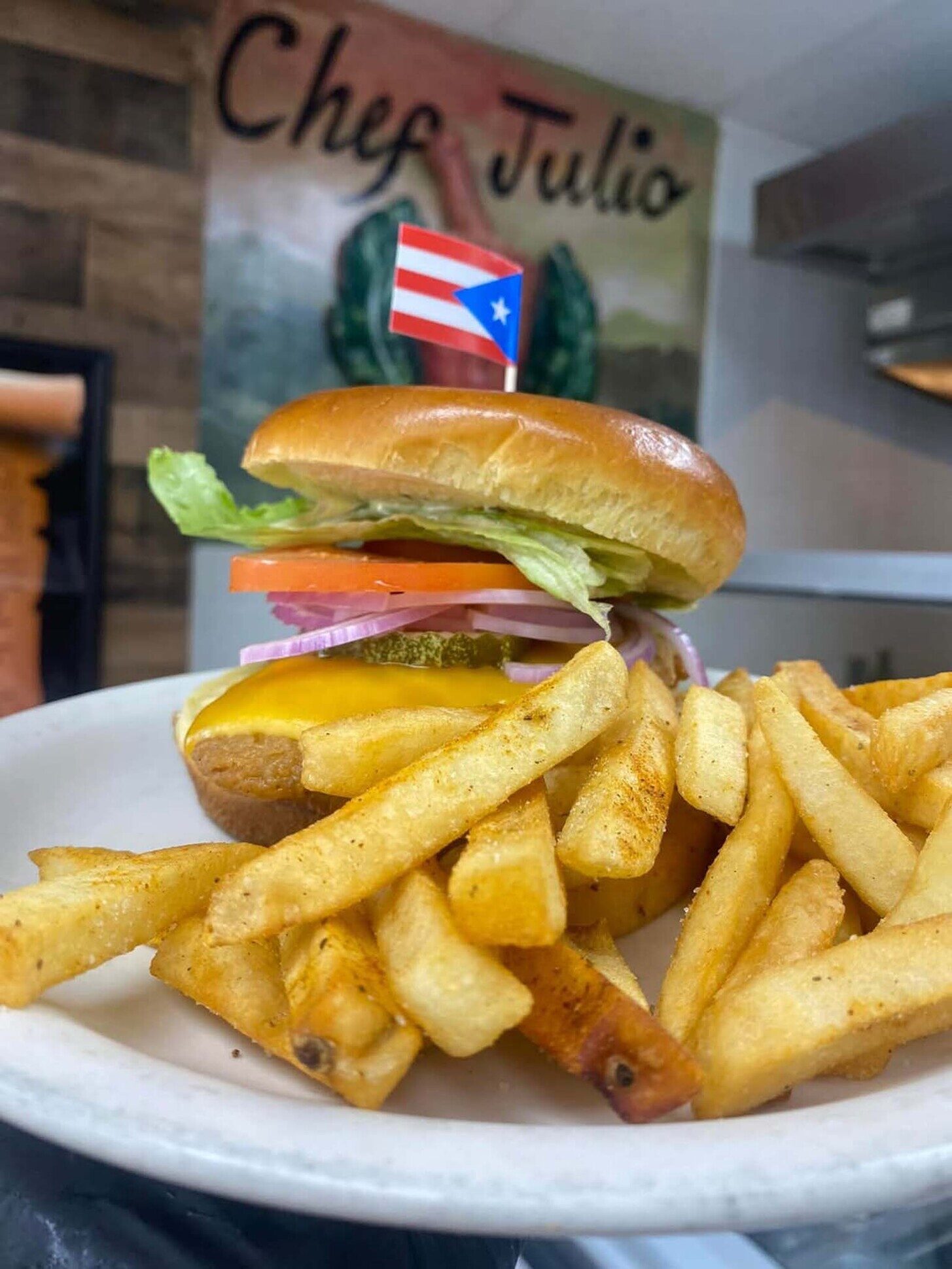 Smash burger with Puerto Rico flag toothpick and seasoned fries at Julio's Empanadas