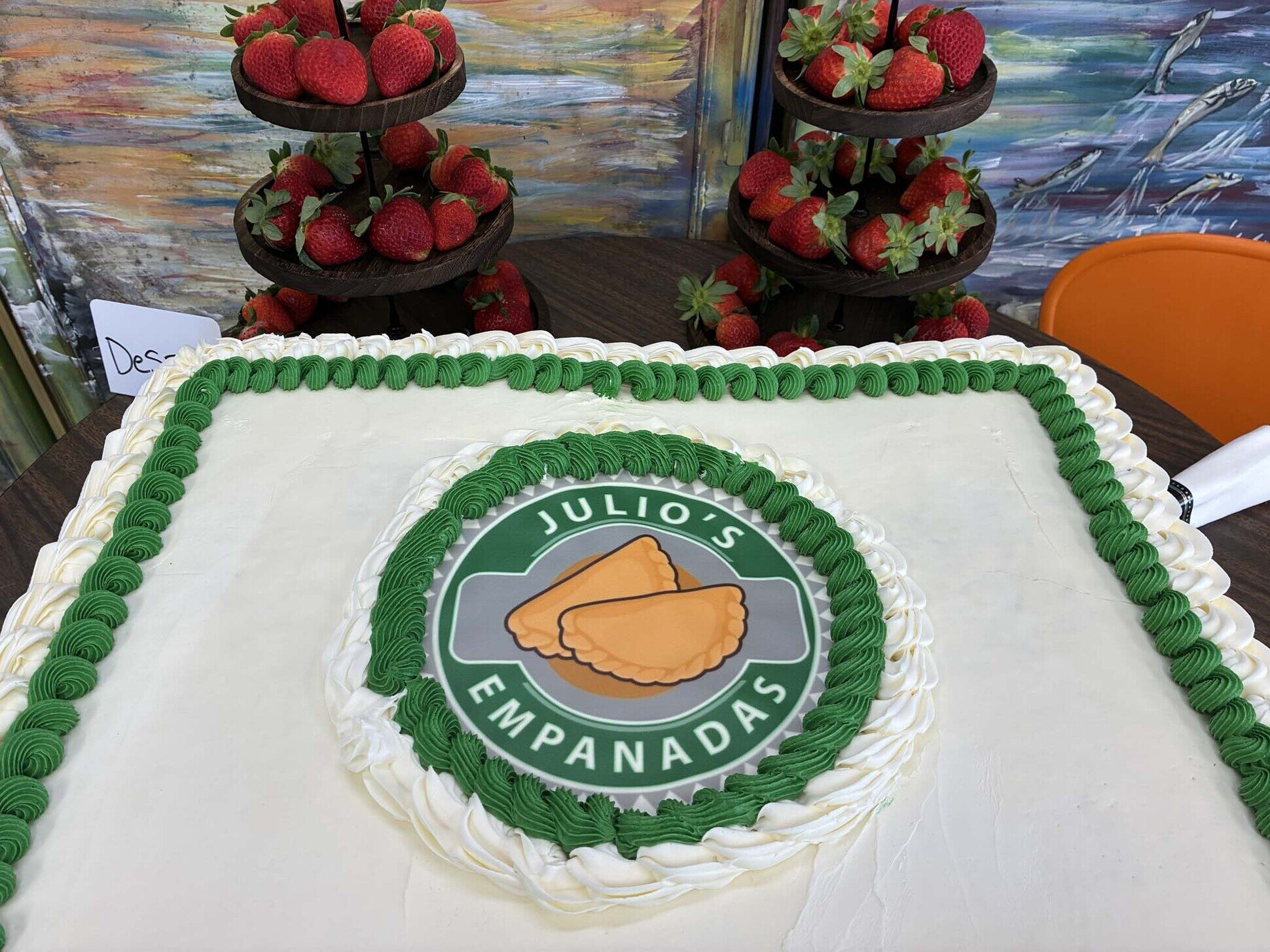 Celebration cake decorated with the Julio's Empanadas logo and tiered strawberry towers